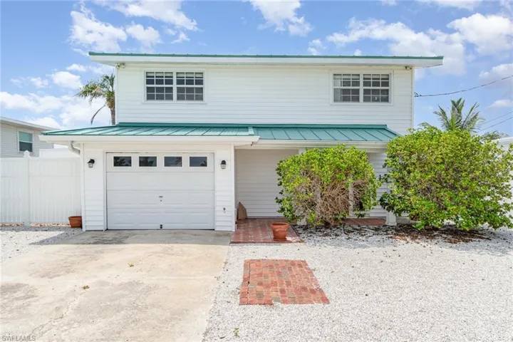 Traditional-style house featuring an attached garage, metal roof, a standing seam roof, and driveway