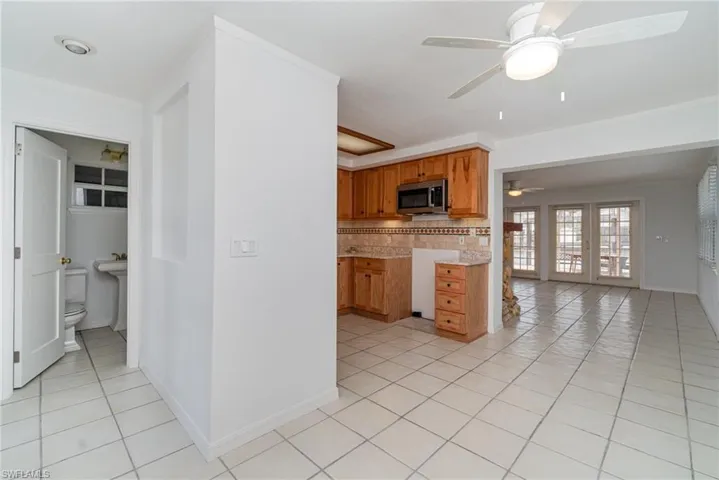 Kitchen featuring stainless steel microwave, ceiling fan, light tile patterned floors, and tasteful backsplash