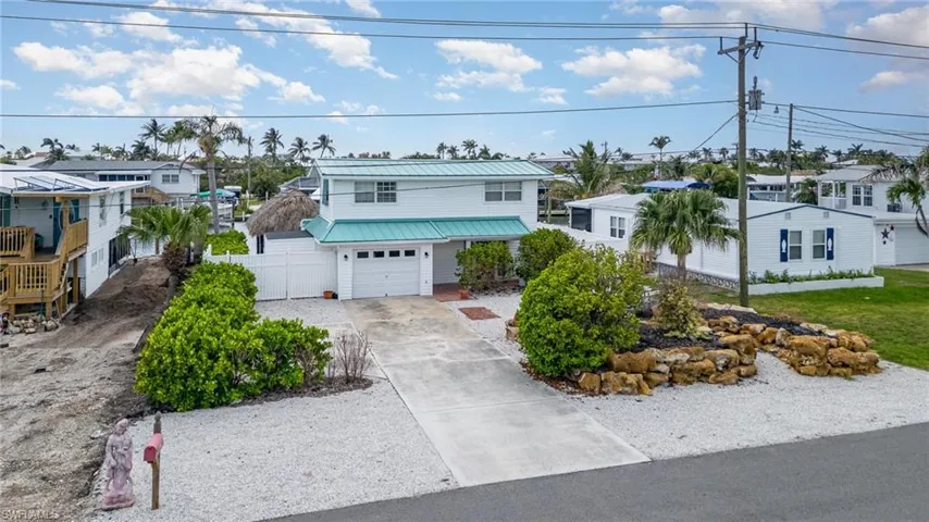 View of front of property with concrete driveway, a residential view, and metal roof