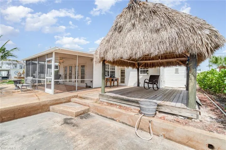 Back of property with a sunroom, a deck, french doors, a patio, and ceiling fan
