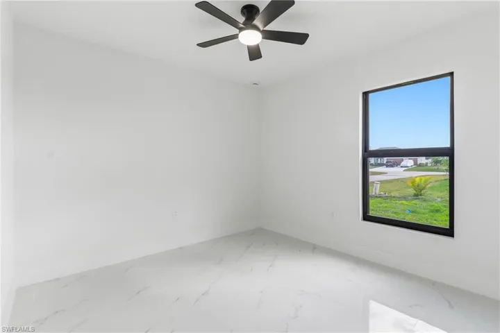 Spare room featuring light marble finish flooring and a ceiling fan