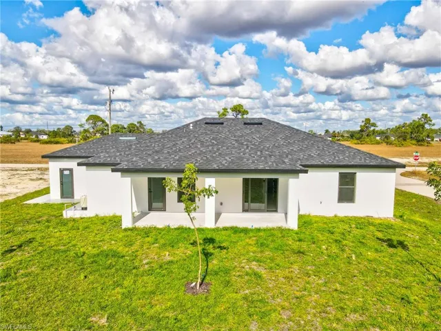 Rear view of property featuring stucco siding, a patio, and a lawn