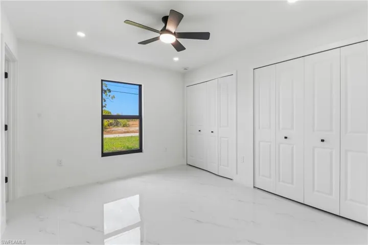 Unfurnished bedroom featuring two closets, light marble finish floors, recessed lighting, and a ceiling fan