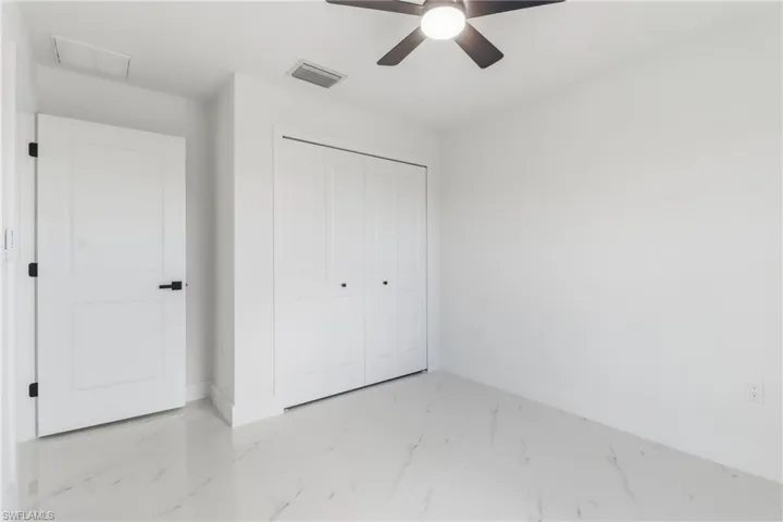 Unfurnished bedroom featuring marble look tile flooring, a closet, and ceiling fan
