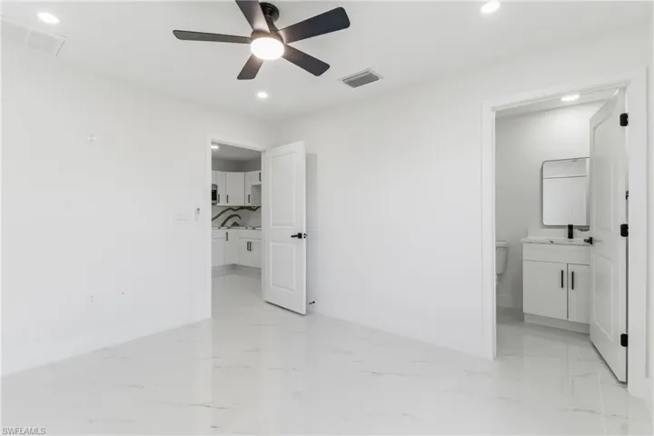 Unfurnished bedroom with ensuite bath, light marble finish flooring, ceiling fan, and recessed lighting
