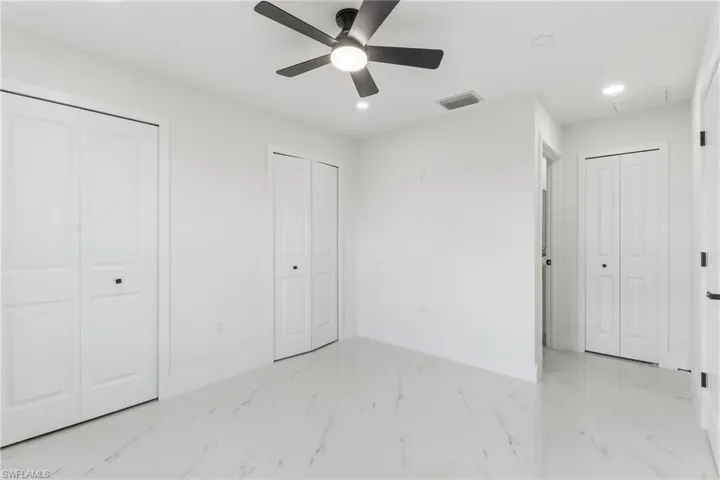 Unfurnished bedroom with two closets, recessed lighting, a ceiling fan, and light marble finish flooring
