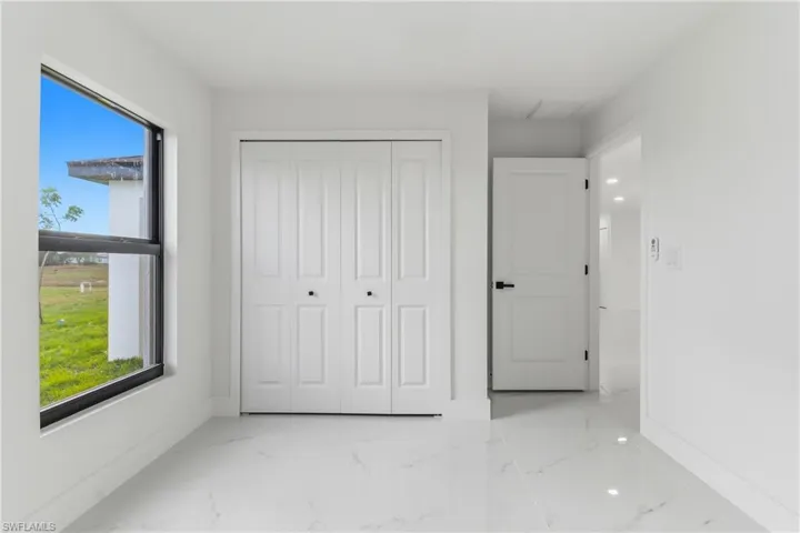 Unfurnished bedroom featuring marble tiled floors and a closet