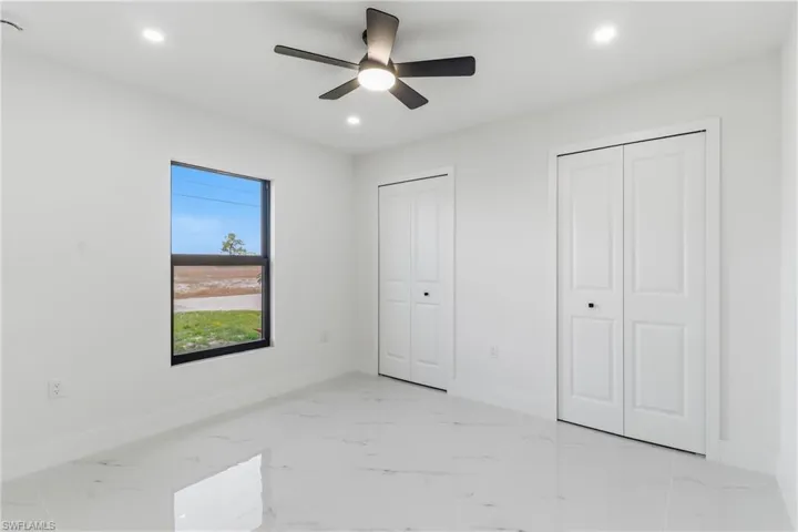Unfurnished bedroom featuring multiple closets, a ceiling fan, light marble finish flooring, and recessed lighting