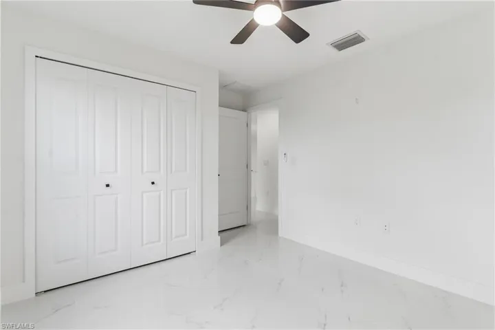 Unfurnished bedroom with a ceiling fan, a closet, and light marble finish flooring