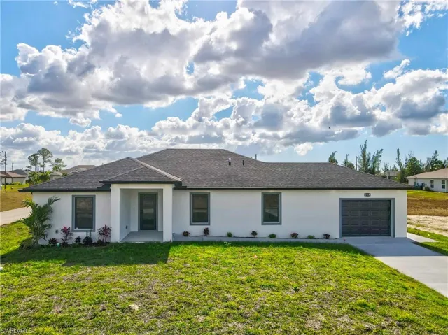 Ranch-style house featuring a front yard, a garage, roof with shingles, and concrete driveway