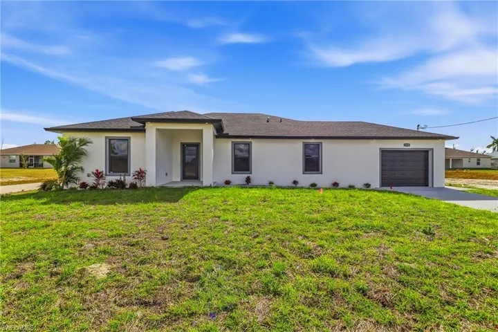 View of front of property featuring a front yard, a garage, concrete driveway, and stucco siding