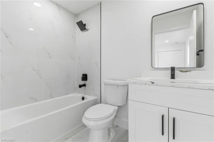 Bathroom with vanity, tub / shower combination, and marble look tile flooring