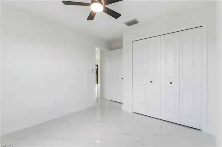 Unfurnished bedroom with light marble finish flooring, ceiling fan, and a closet