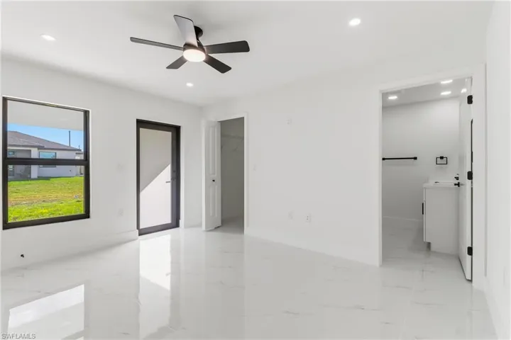 Unfurnished bedroom featuring a spacious closet, light marble finish floors, ceiling fan, and recessed lighting