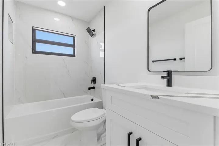 Full bath featuring vanity, a combined bath / shower with marble appearance, marble finish flooring, and recessed lighting