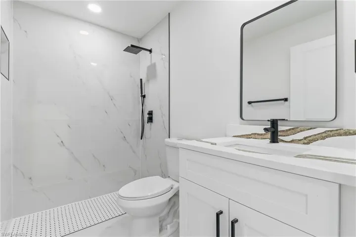 Bathroom with vanity, a marble finish shower, recessed lighting, and marble finish floors