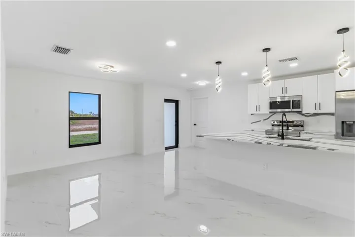 Kitchen featuring white cabinetry, pendant lighting, appliances with stainless steel finishes, light marble finish floors, and recessed lighting