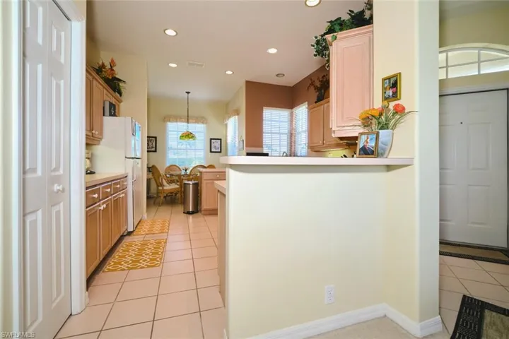 Kitchen with light countertops, light tile patterned floors, a peninsula, pendant lighting, and freestanding refrigerator