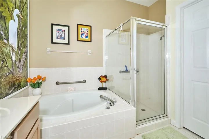 Full bath with vanity, a garden tub, a stall shower, and light tile patterned floors