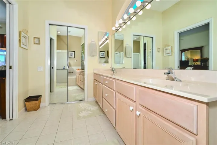 Full bathroom featuring double vanity, light tile patterned floors, and ensuite bathroom
