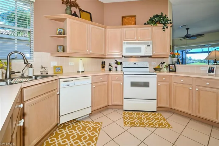 Kitchen featuring light wood finish cabinets, white appliances, and light countertops