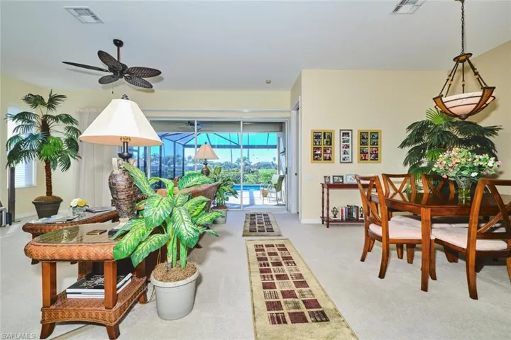 Dining area featuring light colored carpet, a sunroom, and ceiling fan