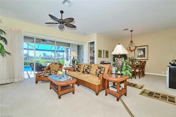 Living room with a sunroom, light carpet, and ceiling fan