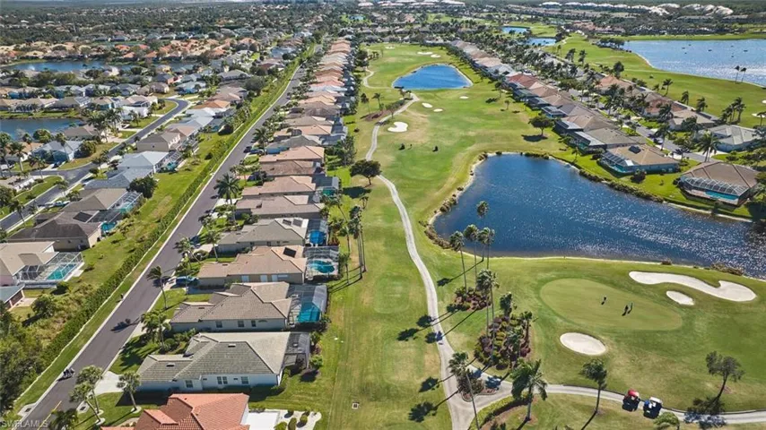 Aerial view of property's location featuring a golf club, nearby suburban area, and a nearby body of water