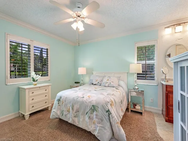 Main bedroom with multiple windows, ceiling fan, crown molding and lake view