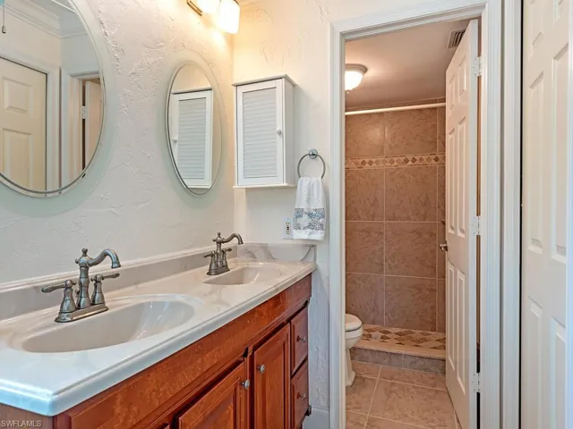 Main bathroom with double vanity, a tile shower, and tile floors