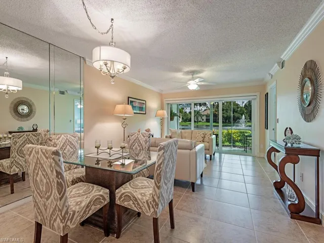 Tiled dining room with ceiling fan with notable chandelier, and crown molding