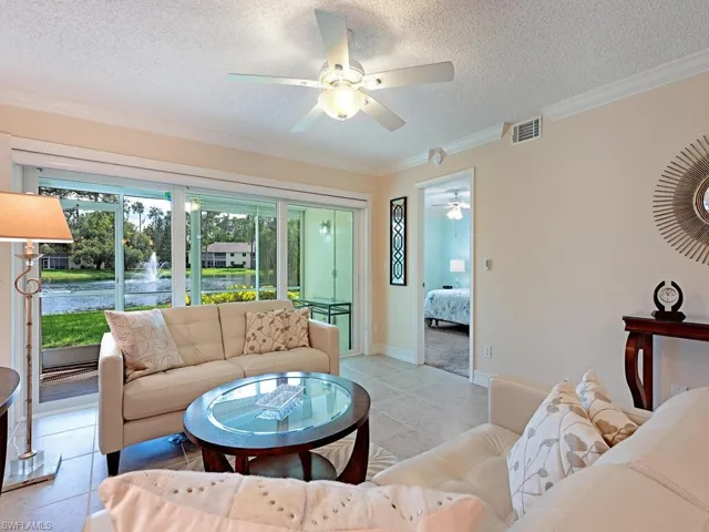 Tiled great room with ceiling fan, crown molding, and lake view