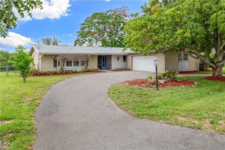 DRIVEWAY VIRTUALLY ENHANCED Curved asphalt driveway leading to a single-story residence with a light stucco exterior