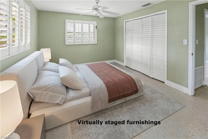 VIRTUALLY STAGED Bedroom featuring plantation shutters, neutral wall color, ceiling fan, bi-fold louvered closet doors,