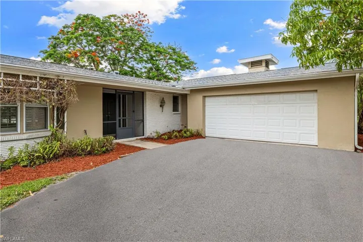 VIRTUALLY ENHANCED DRIVEWAY Exterior featuring a two-car garage, screened entry, stucco and brick facade, asphalt driveway, and mature landscaping