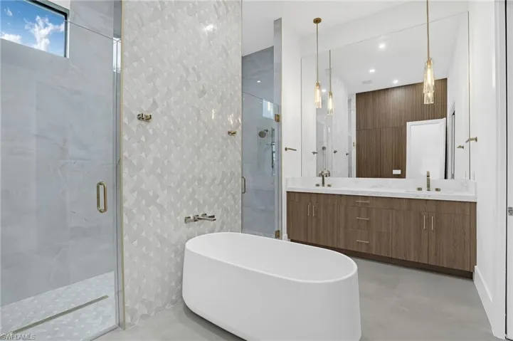 Bathroom featuring a stall shower, double vanity, a soaking tub, and concrete flooring