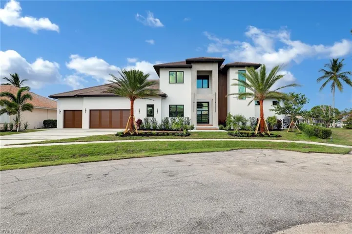 View of front of property featuring a garage, stucco siding, a front yard, and driveway