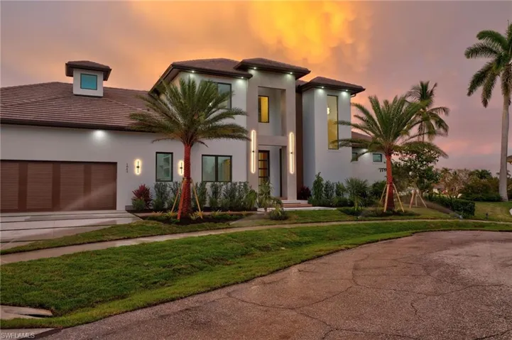 View of front facade with concrete driveway, an attached garage, stucco siding, and a lawn
