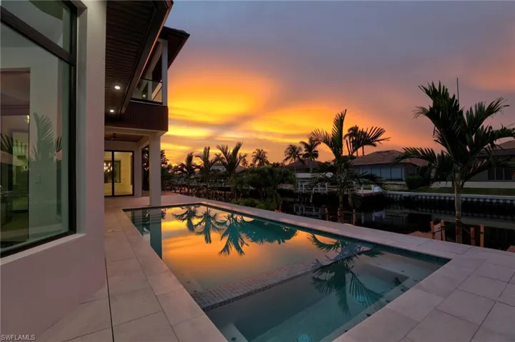 Pool at dusk featuring a pool with connected hot tub and a patio area