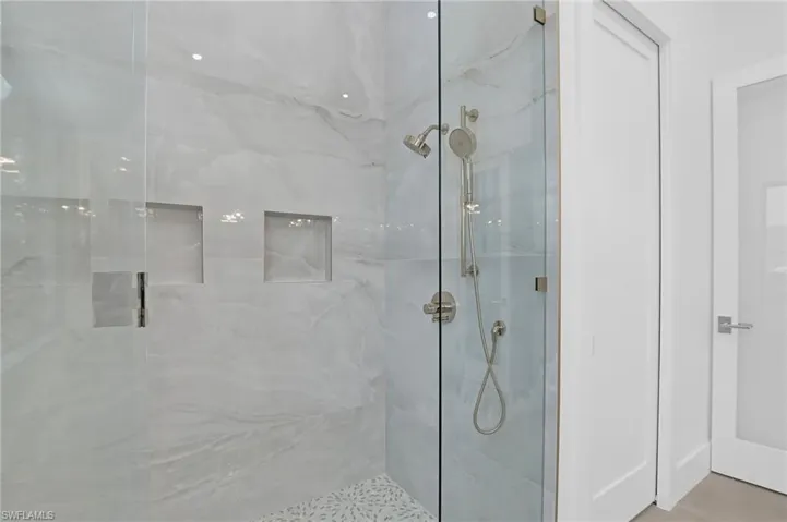 Full bath with a marble finish shower