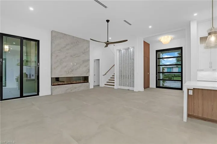 Unfurnished living room featuring stairway, recessed lighting, a fireplace, a ceiling fan, and concrete flooring