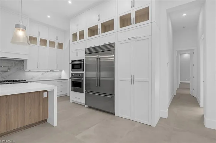 Kitchen featuring stainless steel appliances, backsplash, white cabinets, recessed lighting, and glass insert cabinets