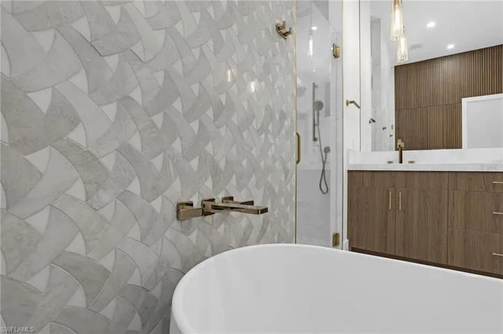 Full bath featuring tile walls, a stall shower, vanity, and a freestanding tub