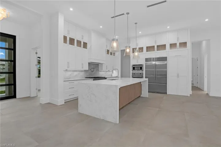 Kitchen featuring appliances with stainless steel finishes, tasteful backsplash, light countertops, a large island, and concrete floors