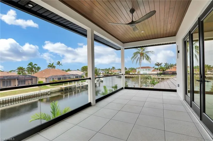 Balcony featuring a water view, a residential view, and a ceiling fan