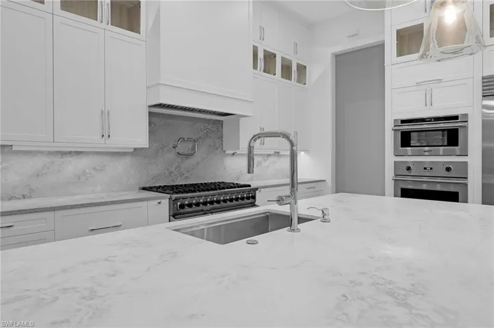 Kitchen featuring white cabinetry, light stone countertops, and tasteful backsplash