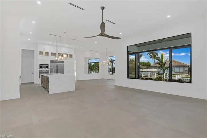 Unfurnished living room featuring ceiling fan, recessed lighting, a chandelier, and concrete flooring