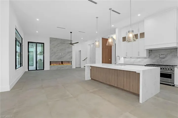 Kitchen with stainless steel range, ceiling fan, a large island, white cabinets, and recessed lighting