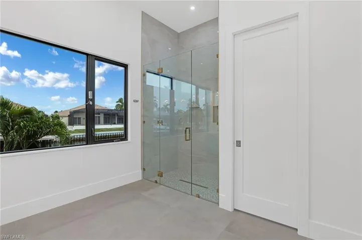 Bathroom featuring a marble finish shower and concrete floors