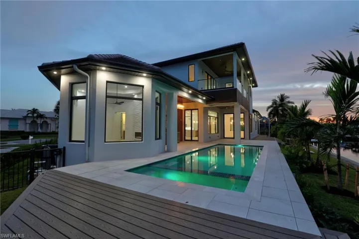 Rear view of house featuring a balcony, stucco siding, an outdoor pool, and a patio area